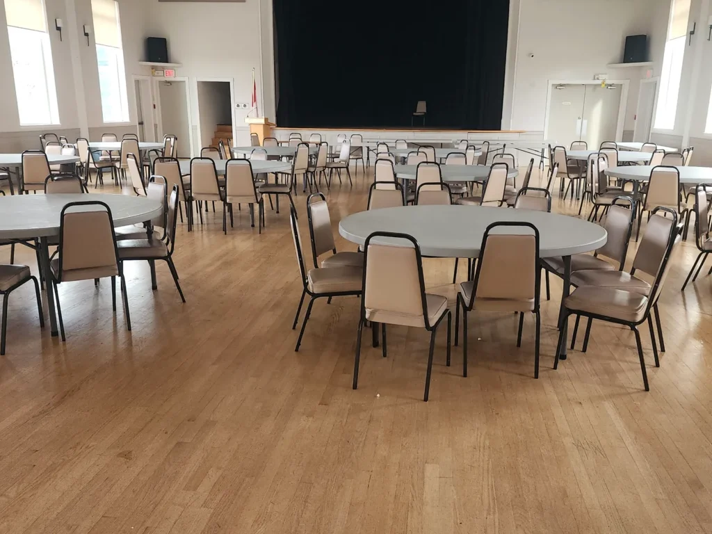 Banquet hall tables and chairs on a dull hardwood floor