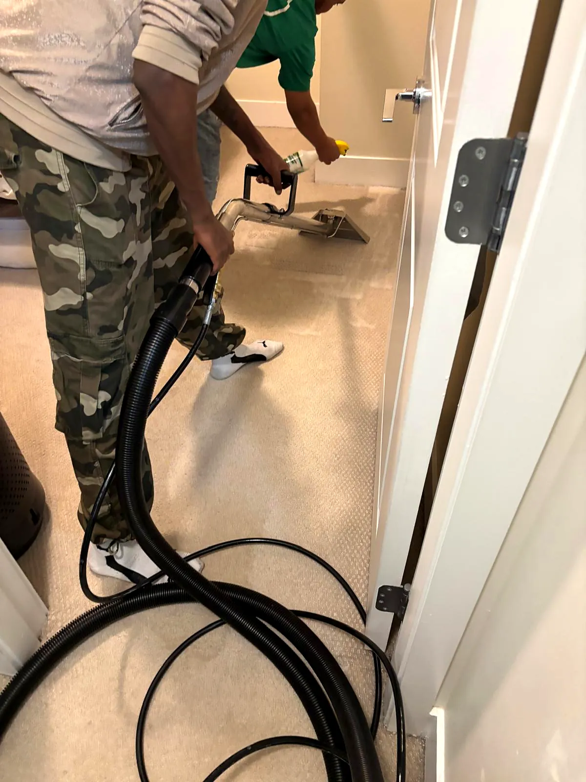 Everest crew member using a carpet extraction wand beside a doorway