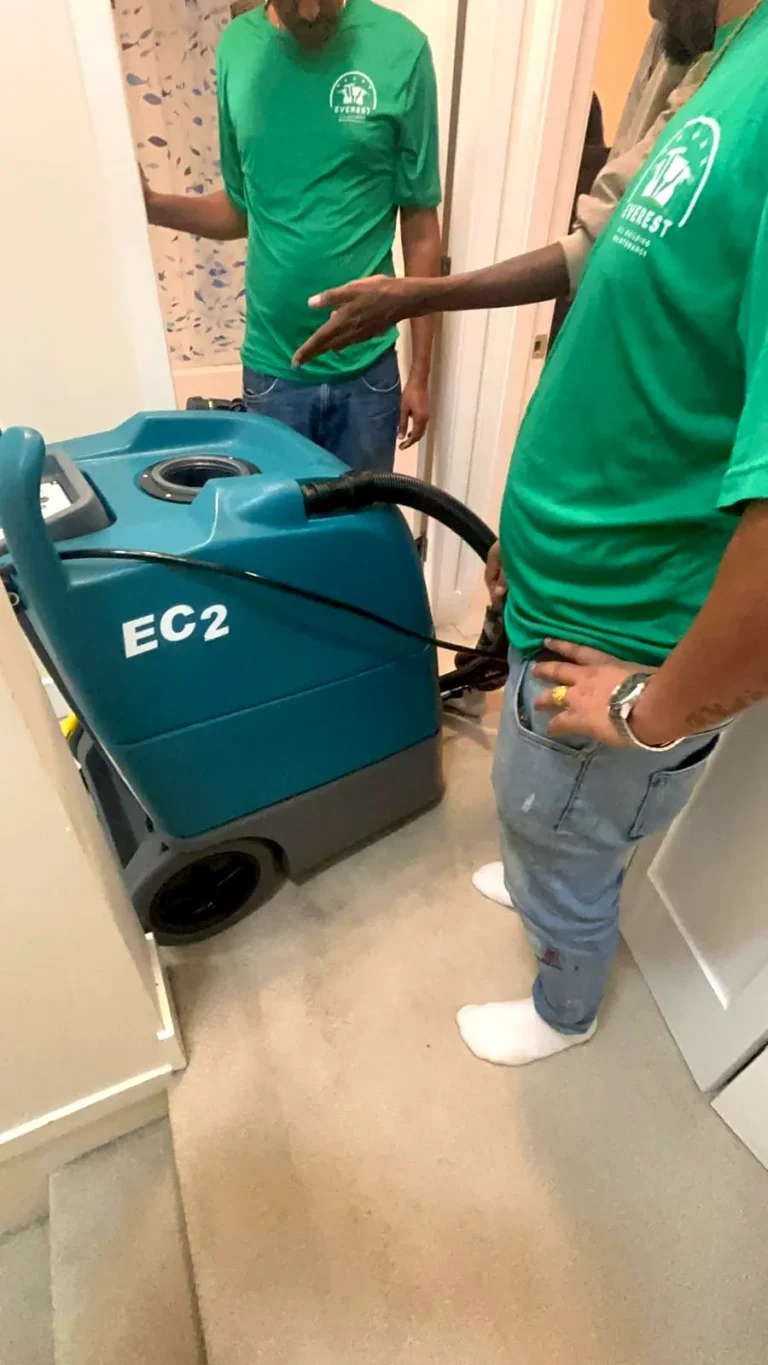 Two crew members beside a teal EC2 carpet extractor
