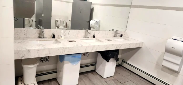Clean marble washroom counter with sinks and soap dispensers