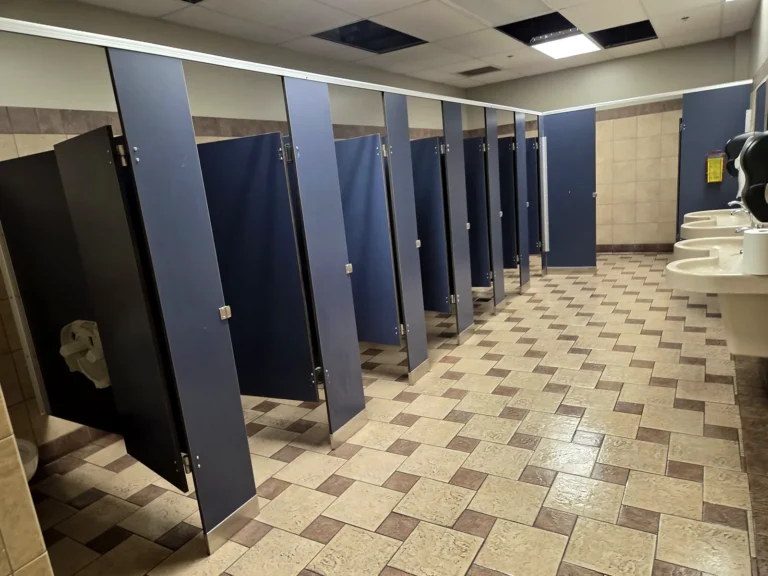 Row of clean washroom stalls with a freshly cleaned tile floor