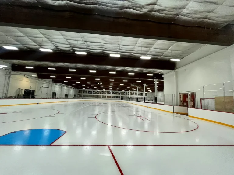 Wide view across an ice rink with a blue crease and red lines