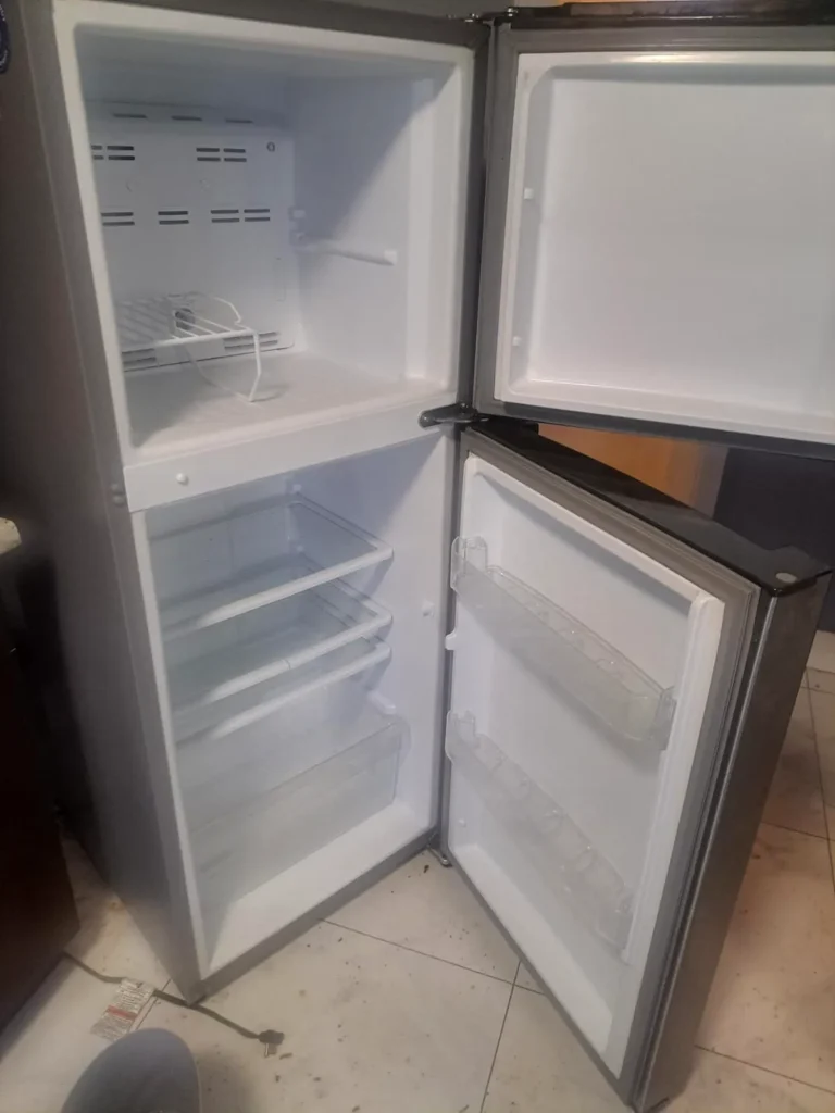 After: clean empty refrigerator with open doors on a tile floor