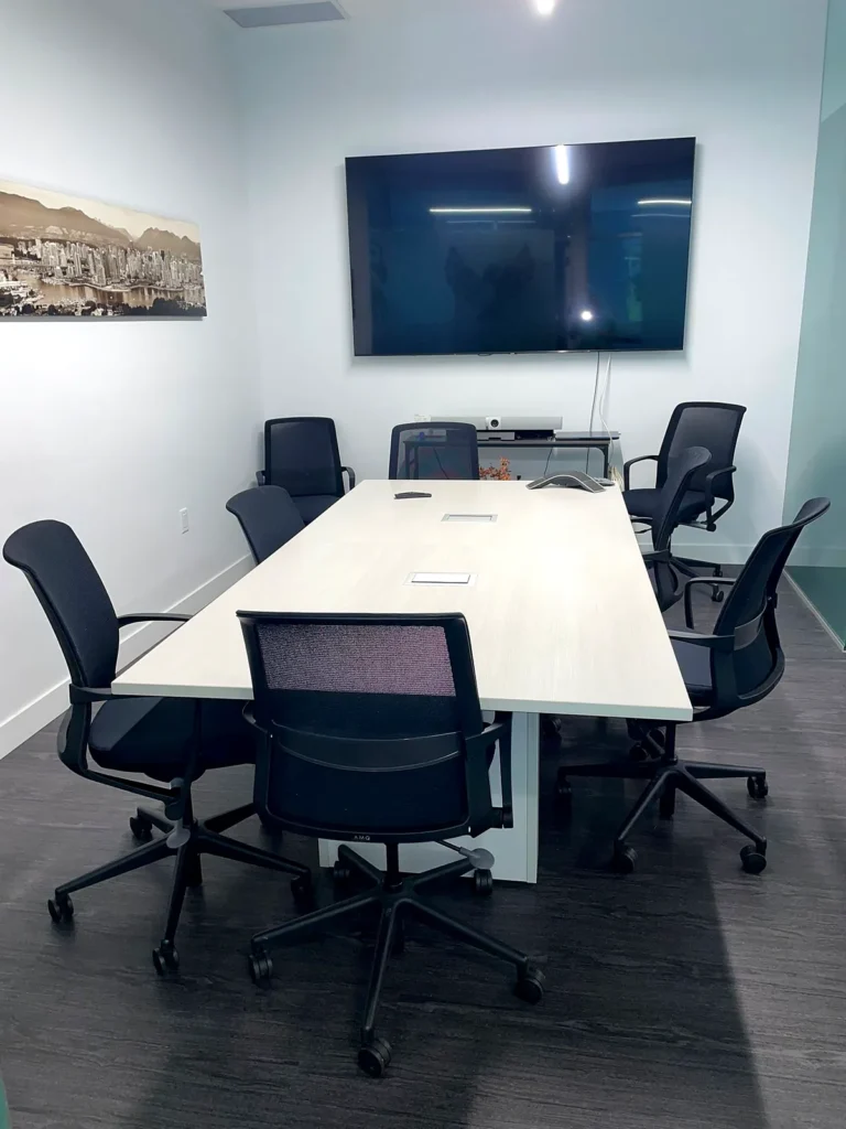 Boardroom with a long table and black chairs, cleaned and ready for meetings