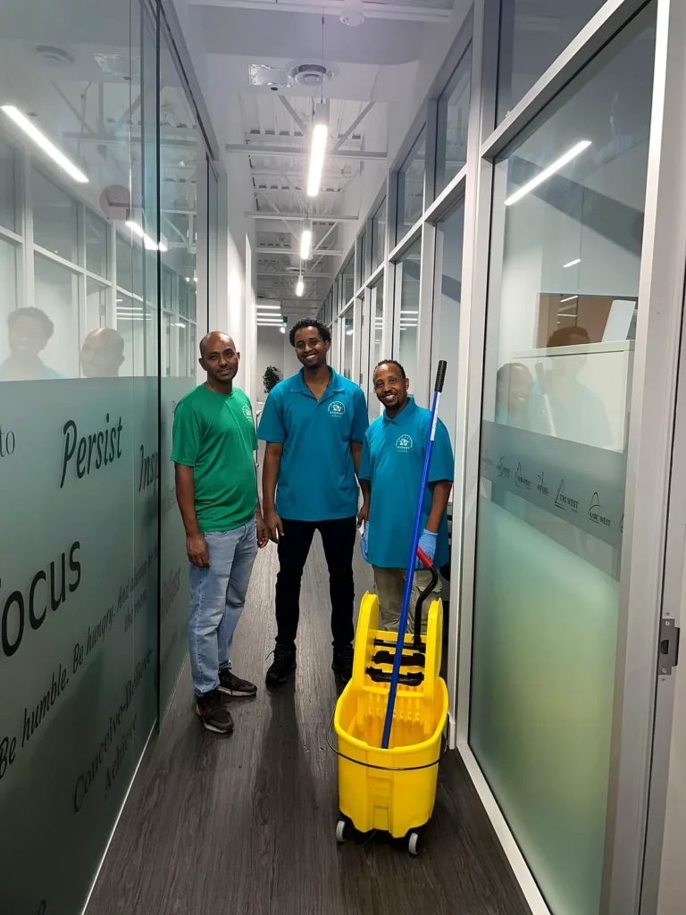 Three Everest crew members with a yellow mop bucket in an office corridor