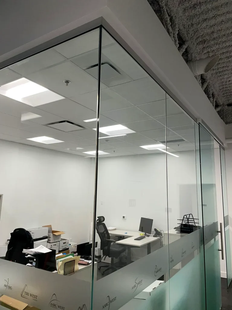 Clean glass-walled office with desks under an exposed ceiling
