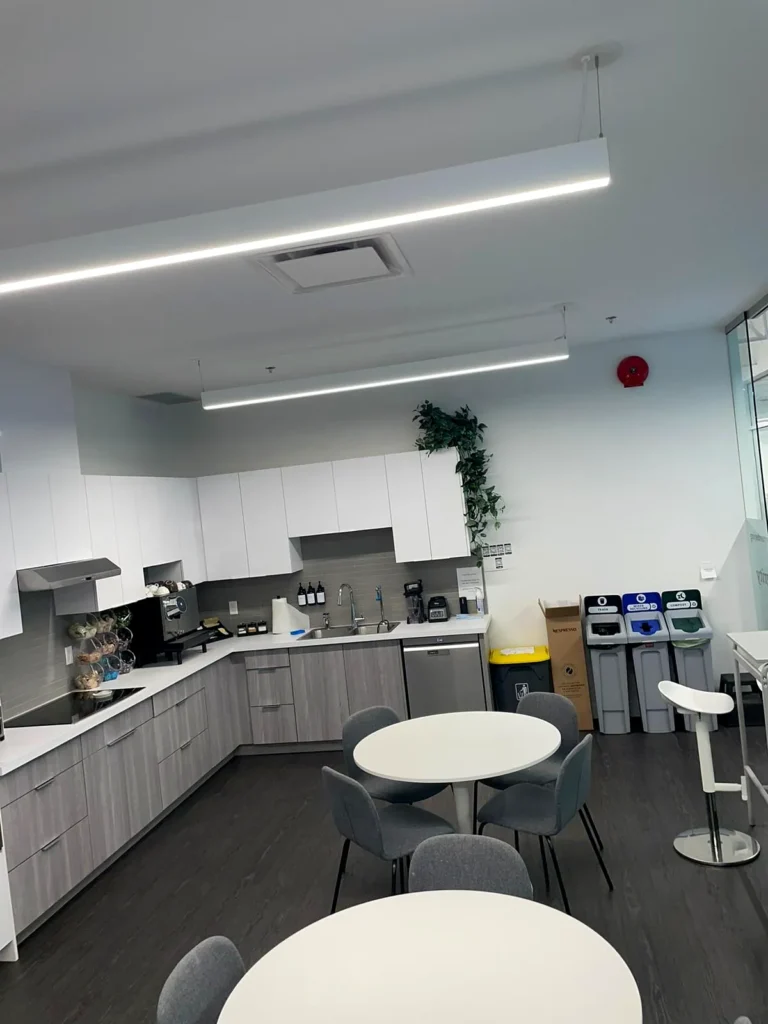 Clean office kitchenette with round tables, grey chairs and white cabinets