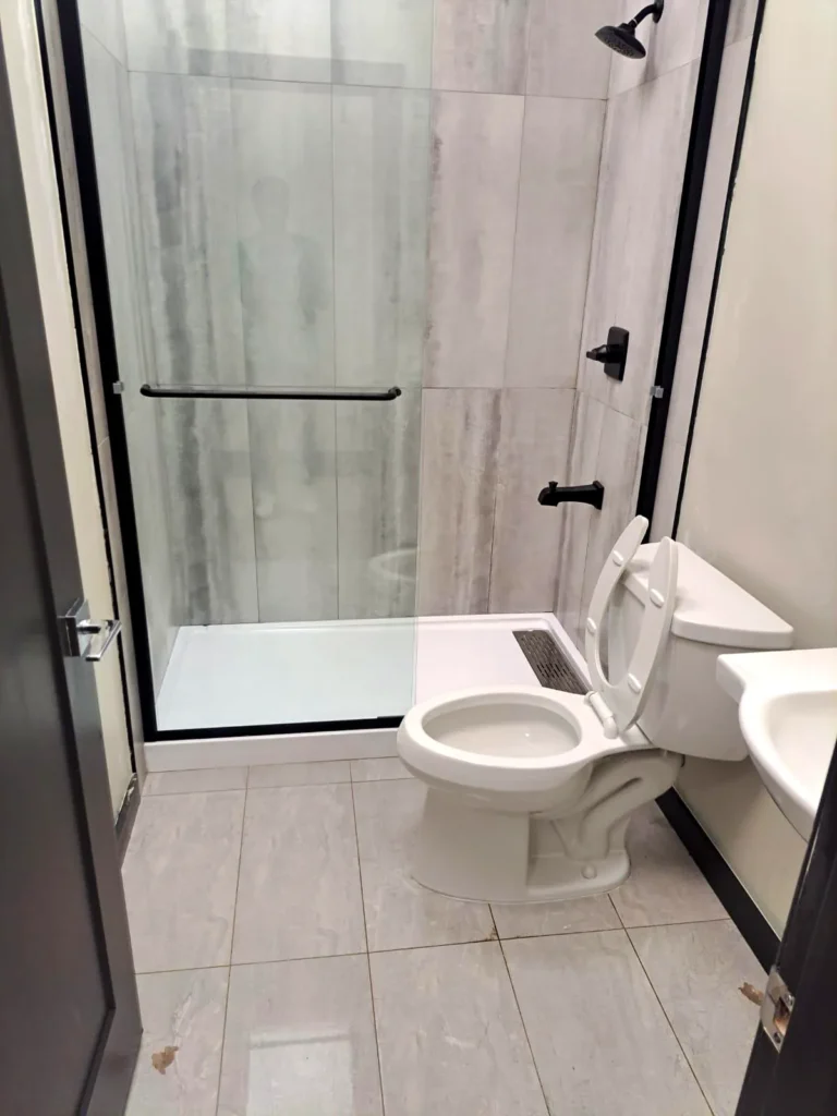 Clean new bathroom with a glass shower, toilet and tile floor