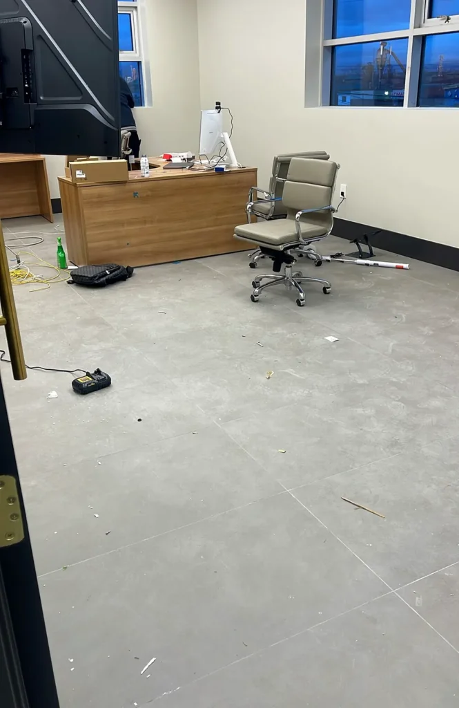 Before: dusty grey floor in an empty new office room with a desk and chair