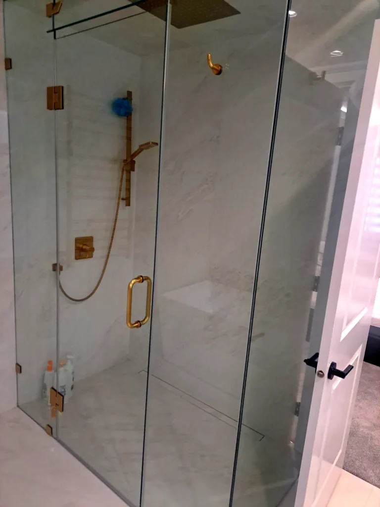 Clean glass shower enclosure with brass fixtures in a home bathroom