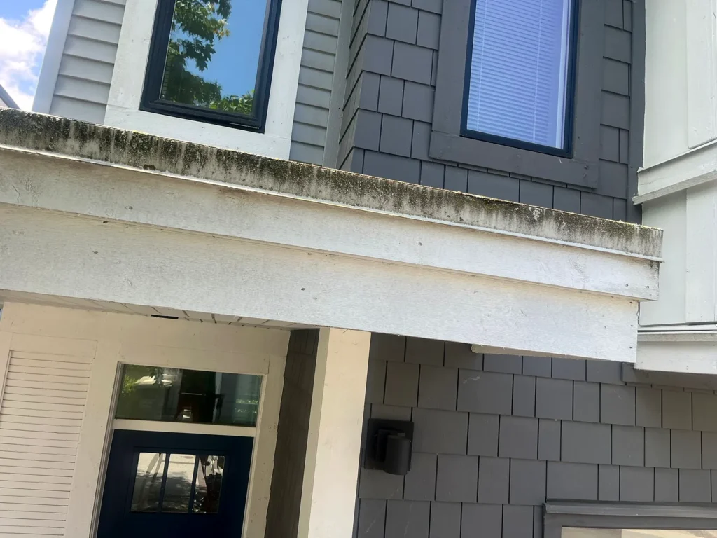 Before: dirty white soffit and siding above a townhouse entrance
