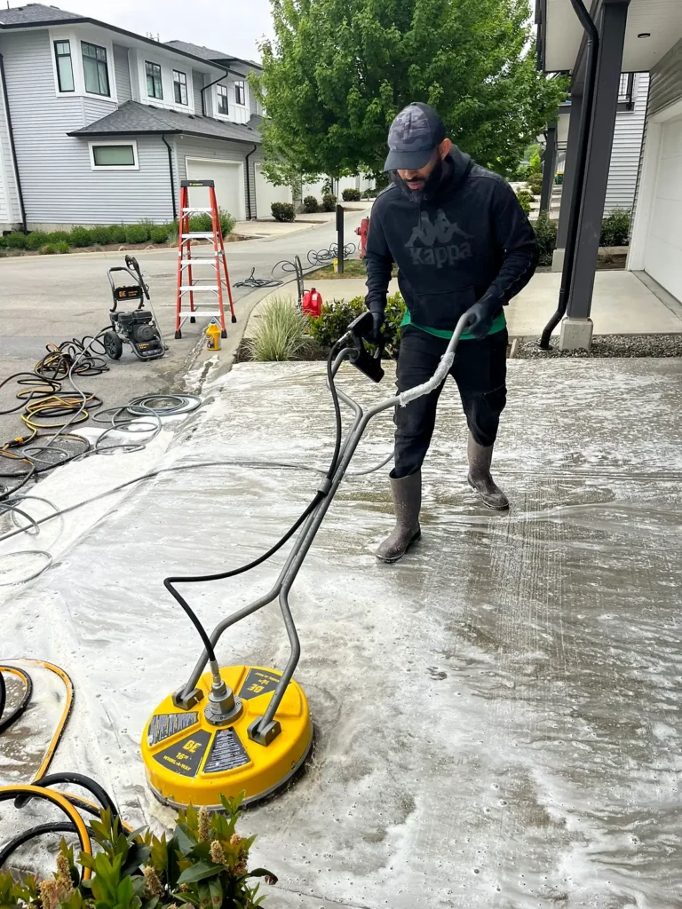 Two crew members washing a townhouse driveway with a surface cleaner and pressure washer